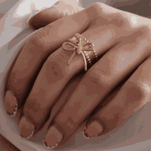 Main féminine portant une bague doré avec nœud suspendu, bijou élégant et minimaliste en acier inoxydable