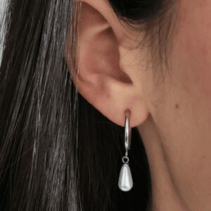 Boucles d'oreilles rondes argenté sur une oreille féminine, orné d'une perle