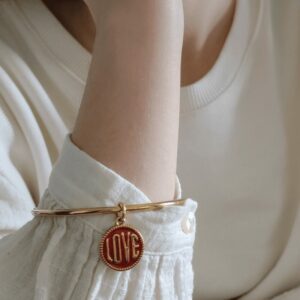 Jonc LOVE Rouge doré porté sur un poignet féminin