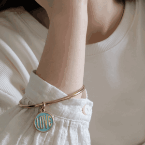 Jonc LOVE Turquoise doré porté sur un poignet féminin