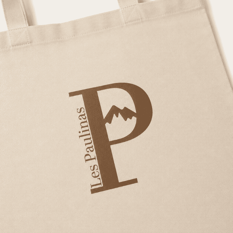 Les Paulinas, gros plan du logo sur le tote bag beige Gros plan sur le logo marron Les Paulinas imprimé sur un tote bag beige en coton nature